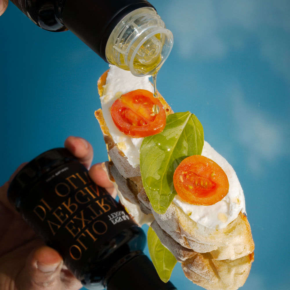 Versamento di olio extra vergine di oliva su una bruschetta